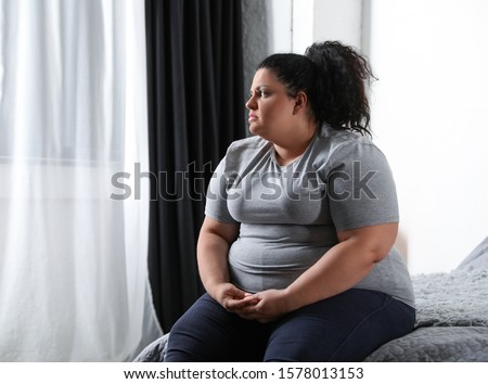Depressed overweight woman on bed at home Photo stock © 