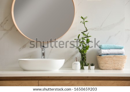 Beautiful green plants near vessel sink on countertop in bathroom. Interior design elements