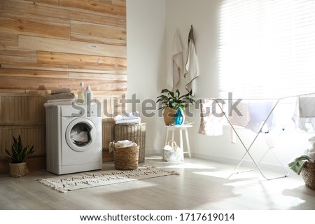 Stylish room interior with modern washing machine and drying rack