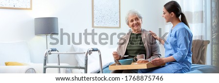 Care worker serving dinner for elderly woman on geriatric hospice. Banner design