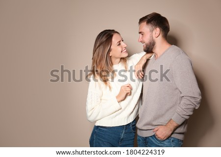 Lovely couple in warm sweaters on beige background