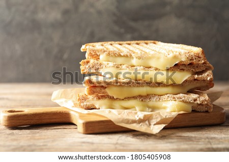 Tasty toast sandwiches with cheese on wooden table