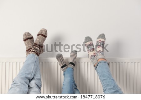 Family warming legs on heating radiator near white wall, closeup Сток-фото © 