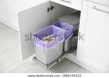 Open cabinet with full trash bins for separate waste collection in kitchen Foto d'archivio © 