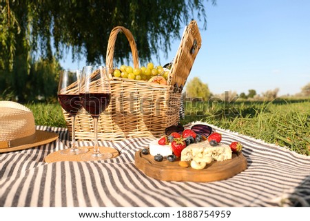 Foto Bild Picknick-Korb mit Wein, Baguette, Weinglas, Blumen, Kerze und Picknick-Decke auf grünem Gras Hintergrund. Romantisches Picknick Vorbereitung im Sommer. Ansicht von oben.