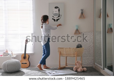 Decorator hanging picture on white wall in baby room. Interior design Foto stock © 