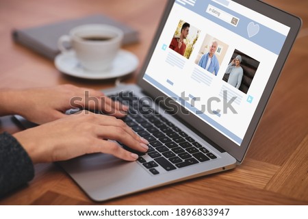 Young woman visiting online dating site via laptop at table, closeup 商業照片 © 