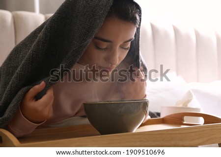 Woman with plaid doing inhalation above bowl indoors
