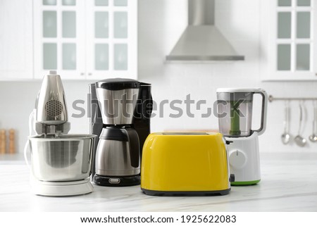 Modern toaster and other home appliances on white marble table in kitchen