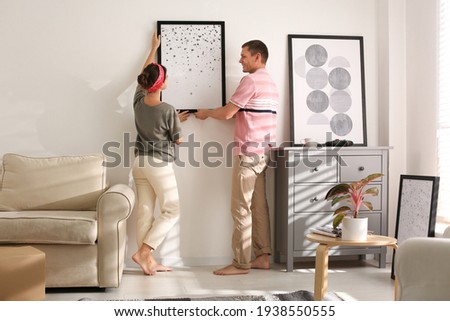 Couple decorating room with pictures together. Interior design Stockfoto © 