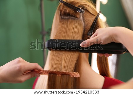 Stylist straightening woman's hair with flat iron in salon ストックフォト © 