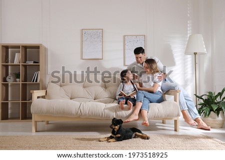 Photo of Happy family on sofa and puppy in living room