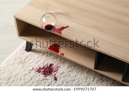 Overturned glass and spilled red wine on white carpet indoors Foto stock © 