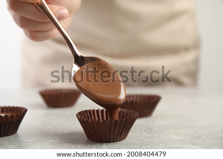 Professional confectioner making delicious chocolate candies at grey table, closeup Foto stock © 
