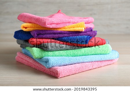 Stack of colorful microfiber cloths on light wooden table, closeup Imagine de stoc © 