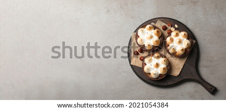 Delicious salted caramel chocolate tarts with meringue and hazelnuts on grey table, top view. Space for text Stok fotoğraf © 
