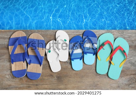 Pairs of flip flops on wooden deck near swimming pool, flat lay  Stock fotó © 