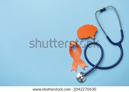 Orange ribbon, stethoscope and paper brain cutout on light blue background, flat lay with space for text. Multiple sclerosis awareness 商業照片 © 