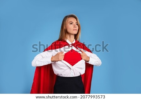 Confident businesswoman wearing superhero costume under suit on light blue background Foto d'archivio © 