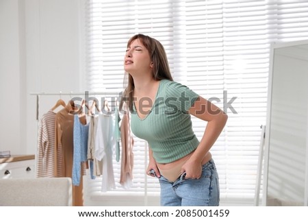 Young woman struggling to put on tight jeans at home Photo stock © 
