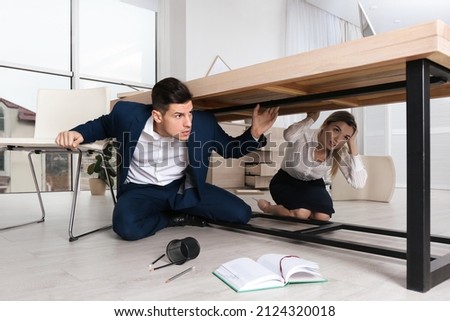 Scared employees hiding under office desk during earthquake Сток-фото © 