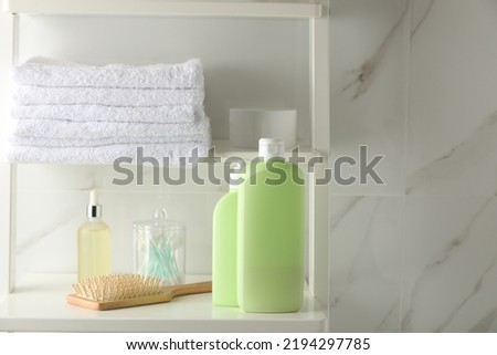Stack of towels, hairbrush, shampoo and other toiletries on shelves near white marble wall ストックフォト © 