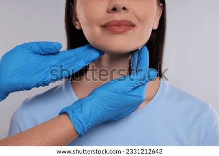 Endocrinologist examining thyroid gland of patient on light grey background, closeup Foto stock © 