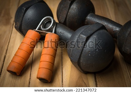 Hand Gripper and dumbbell on wooden