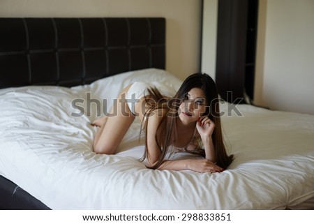 sexy brunette woman on the bed wearing white bikini