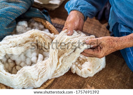 Craftsmen of Thai indigo cotton. An elderly woman is examining the thread made of cotton. Local Master are the original Indigo Cotton Weaving in the community of Sakon Nakhon province.