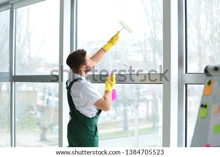 Male janitor cleaning window in office Foto stock © 
