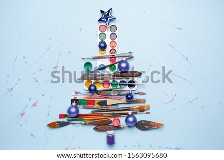 Beautiful Christmas tree made of painter tools on color background