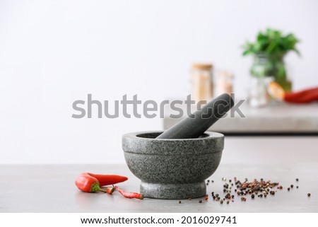 Mortar with spices and pestle on light table in kitchen Foto d'archivio © 