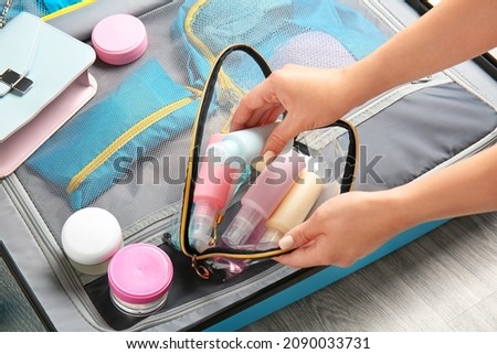 Female hands, bag with travel cosmetics kit and suitcase on floor Stockfoto © 