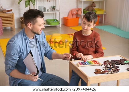 Similar – Image, Stock Photo Boy with Autism communicating with ipad while eating a homemade gluten free muffin; plastic animal toys nearby