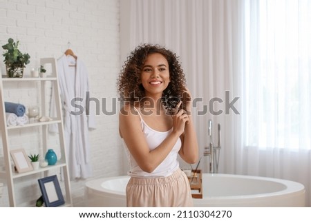 Young African-American woman with healthy hair in bathroom Foto stock © 