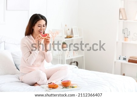 Morning of young Asian woman eating grapefruit in bedroom Stok fotoğraf © 