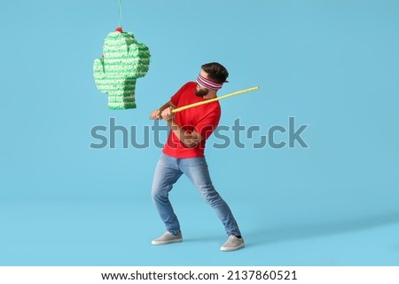 Handsome man breaking Mexican pinata on color background Сток-фото © 