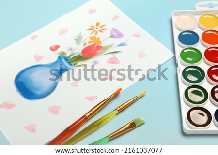 Picture with paints and brushes on blue background. Mother's Day celebration