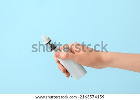 Female hand with modern vape mod on blue background Imagine de stoc © 