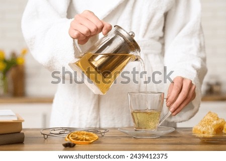 Similar – Image, Stock Photo Woman pouring green tea in mug on wooden table with green herb