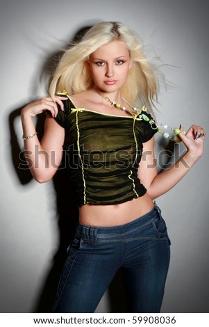 Glamorous young woman in shirt and jeans on gray background