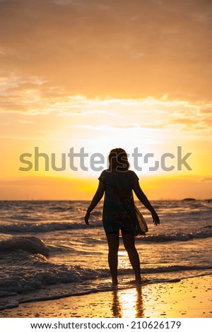 Young lady dances alone at the beach, sunset