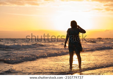 Beautiful dancing woman hands up sunset silhouette