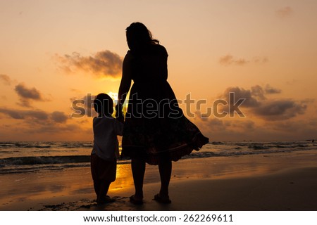 Silhouette of mother and little daughter on the beach