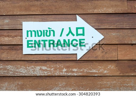 Entrance sign with direction arrow on wooden background