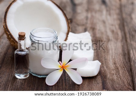 Coconut oil and fresh coconut fruit on wooden table background. Closeup.