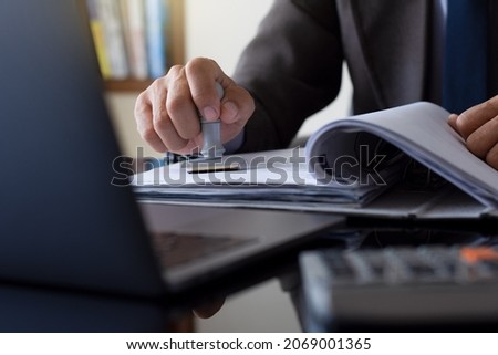 Businessman in suit hand stamping rubber stamp on document in folder with laptop computer on the desk at office. Authorized allowance permission approval concept. Foto d'archivio © 