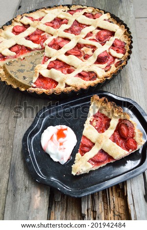 Strawberry tart on a black plate and background with wooden planks
