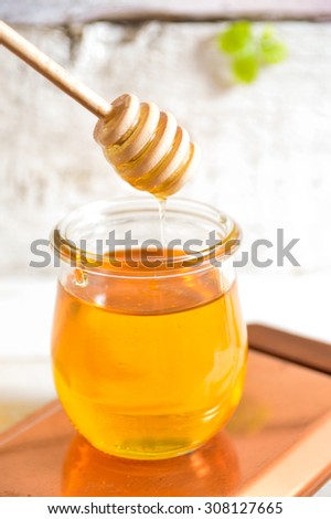Honey drip in jar on the table. Old board background